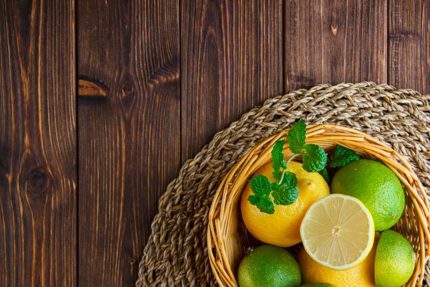 Limes with lemons, herbs in a wicker basket on wooden table