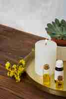 Free photo limonium flower with white large lighted candle and essential oil bottle on wooden desk