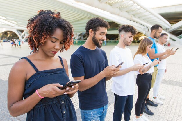 Line of mix raced people texting messages on smartphones