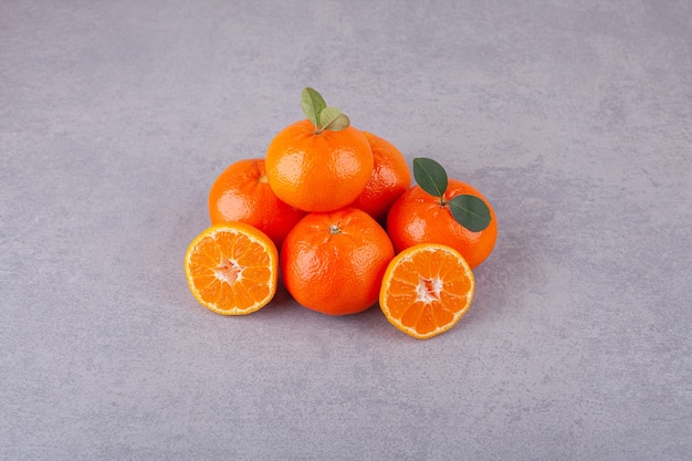 Linea di frutti di mandarino dolce con foglie poste su una pietra.