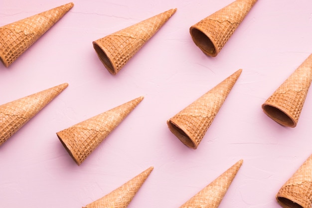Lined empty ice cream cones on pink background