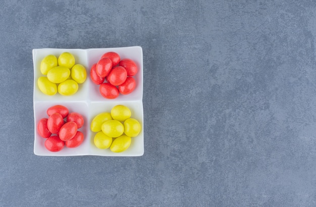 Free photo lined gums on the plate, on the marble background.