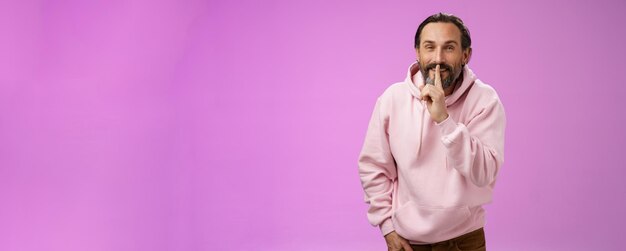 Lips sealed secret portrait alluring cheeky stylish adult bearded guy in pink hoodie asking keep