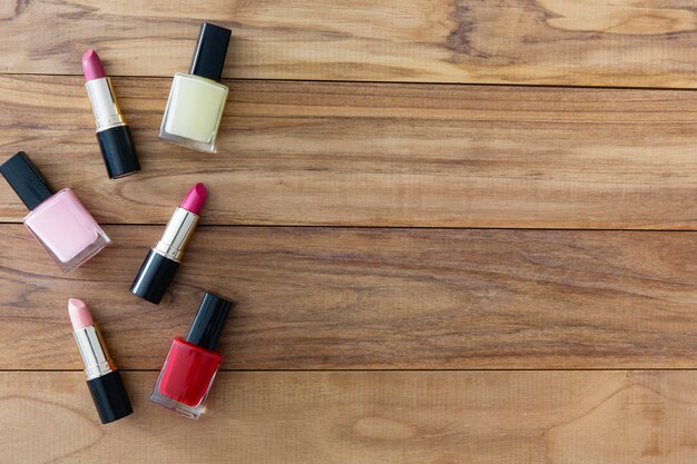 Lipsticks and nail polishes on wooden background