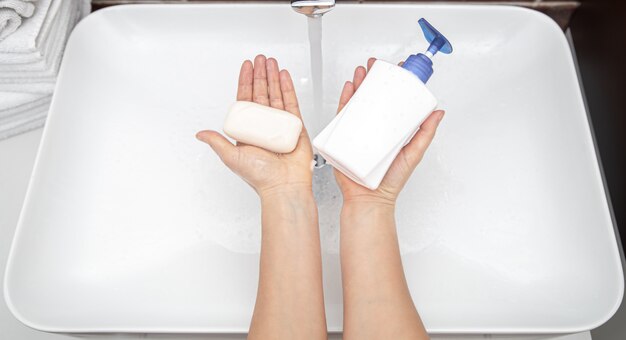 Liquid soap and solid soap in female hands top view..  personal hygiene and health.