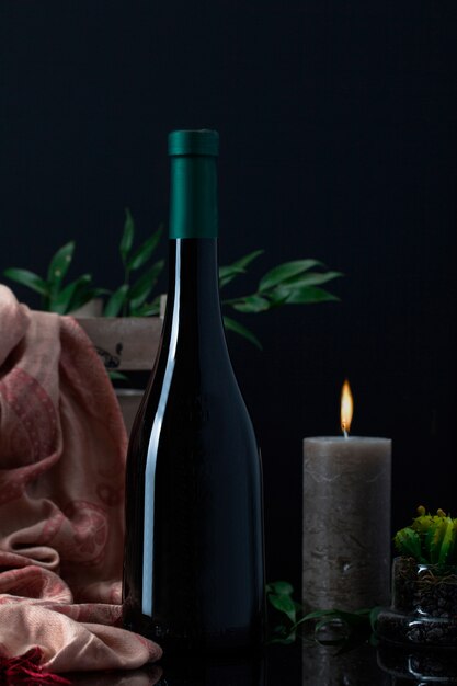 Liquor bottle with candle, scarf and plant in pot