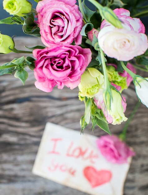 사랑한다는 메시지가 담긴 나무 탁자에 있는 리시안투스 꽃다발