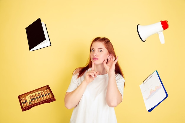 Foto gratuita ascolta qualcuno. ritratto della giovane donna caucasica su sfondo giallo studio, troppe attività. come gestire il tempo nel modo giusto. concetto di lavoro, affari, finanza, freelance, autogestione, pianificazione.