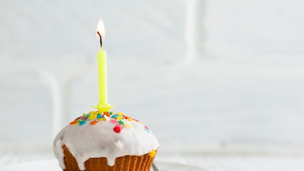 Lit candle on cupcake with white glaze