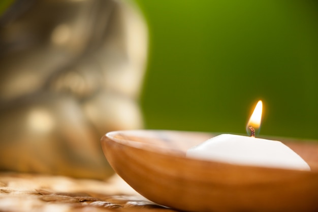 Lit candle in wooden bowl