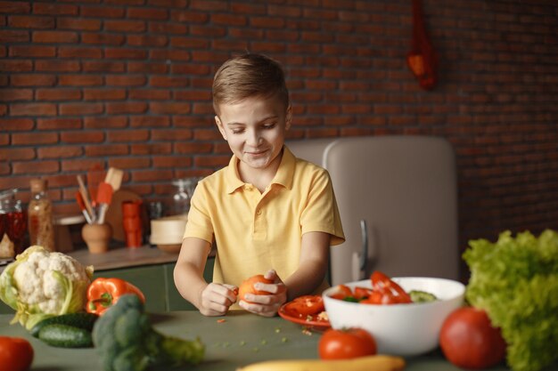 Il ragazzino prepara salan in una cucina