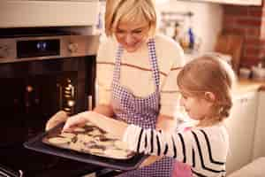 Free photo litlle girl helping grandmother while baking