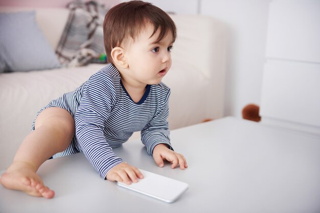 Little baby climbing with cell phone on the table