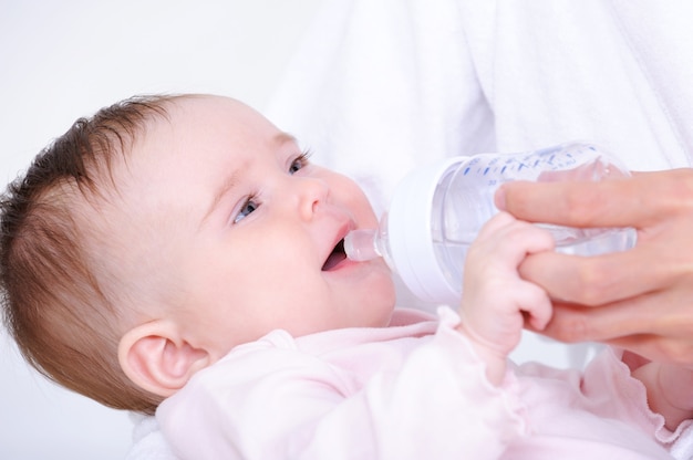 Маленький ребенок пьет молоко из бутылки