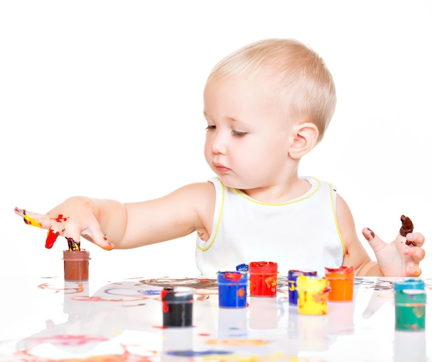 Little baby paint by his hands - on white wall.