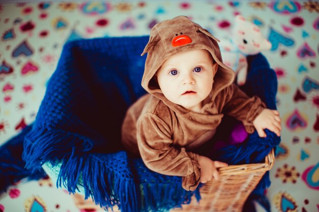 Little baby sits in a wicker basket.