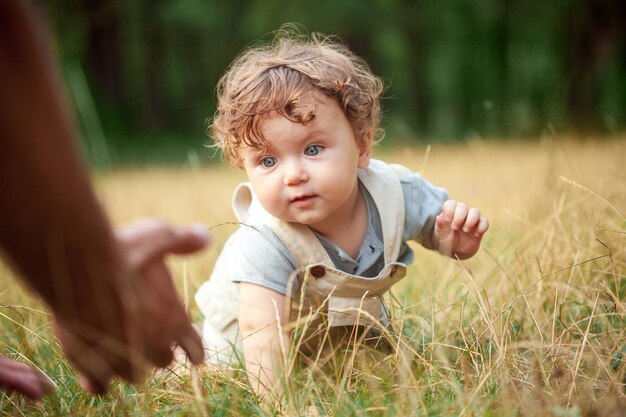 The little baby or year-old child on the grass in sunny summer day