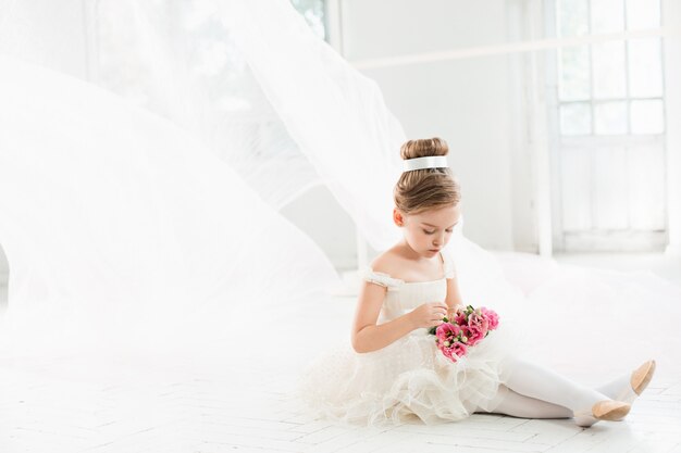 The little balerina in white tutu in class at the ballet school