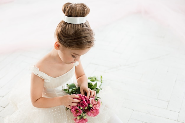 little balerina in white tutu in class at ballet school