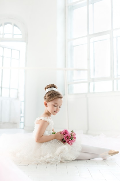 little balerina in white tutu in class at ballet school