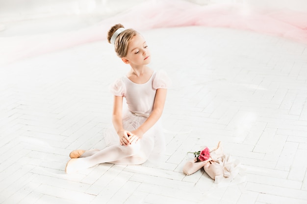 The little balerina in white tutu in class at the ballet school