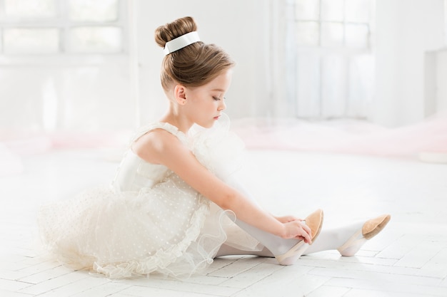 The little balerina in white tutu in class at the ballet