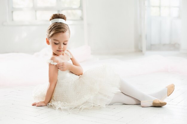 The little balerina in white tutu in class at the ballet