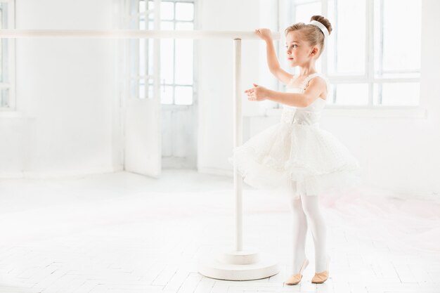 Little ballerina girl in a tutu. Adorable child dancing classical ballet in a white studio.