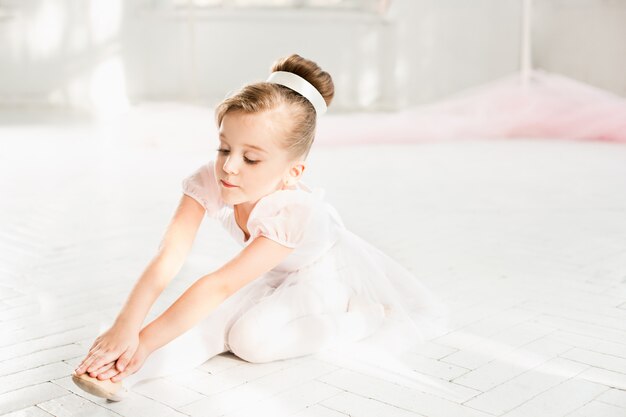 Little ballerina girl in a tutu. Adorable child dancing classical ballet in a white studio.