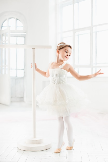 Little ballerina girl in a tutu. Adorable child dancing classical ballet in a white studio.