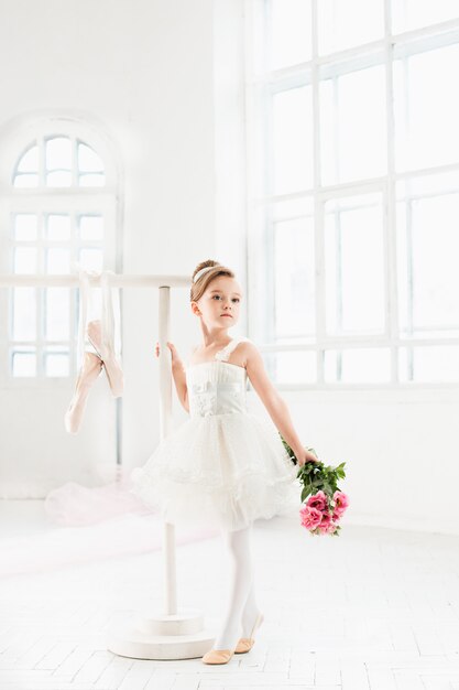 チュチュのバレリーナ少女。白いスタジオでクラシックバレエを踊る愛らしい子。