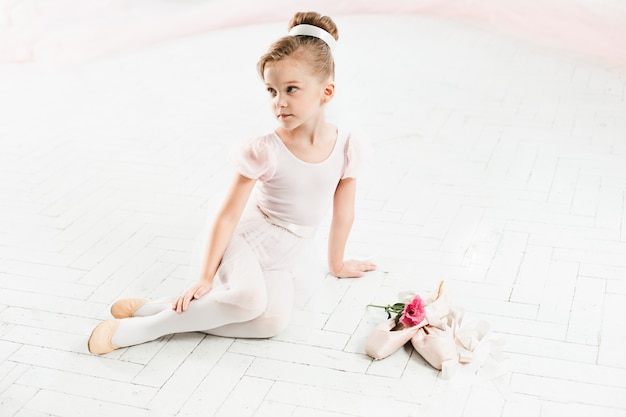 little ballerina in white tutu in class at the ballet school