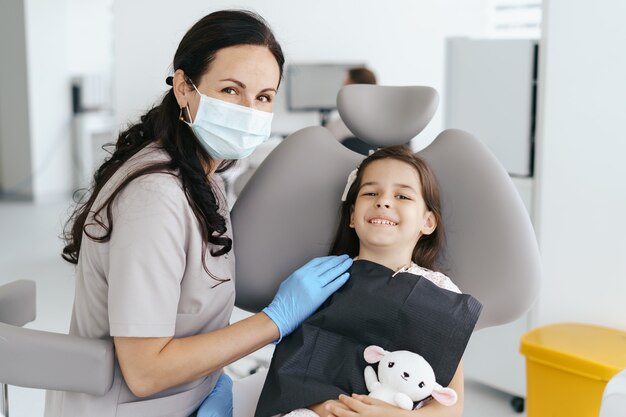 見て笑っている歯科医の小さな美しい少女