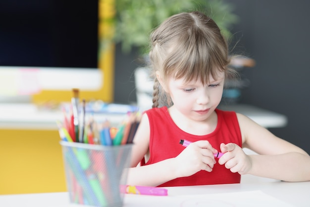 어린 아름다운 소녀는 집에서 연필을 그립니다. 아이들의 미세 운동 능력 개발 프리미엄 사진