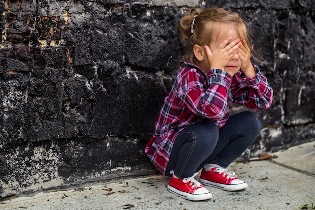 Free photo little beautiful girl near brick wall