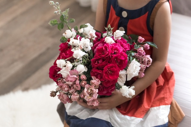 Little beautiful girl with a bouquet of roses