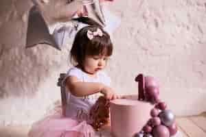 Foto gratuita piccola festa di compleanno affascinante bambino in abito rosa si siede sulla sedia