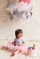 Free photo little birthday girl. charming baby in pink dress sits on the chair