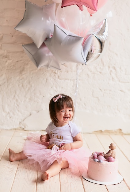 작은 생일 소녀. 핑크 드레스에 매력적인 아기는 의자에 앉아