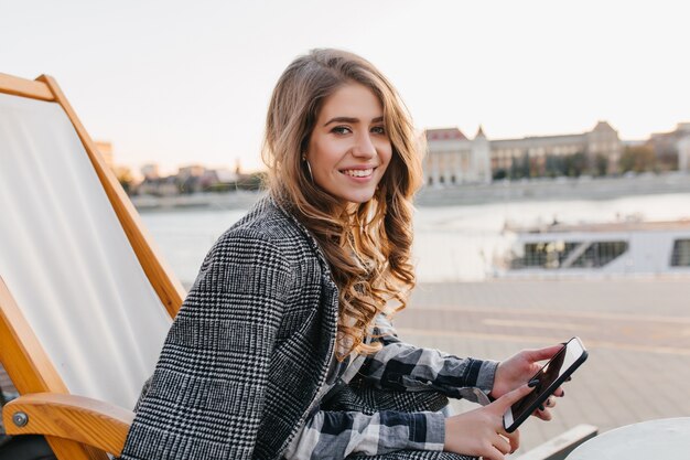 Little bit tired young woman in warm coat posing in recliner in square