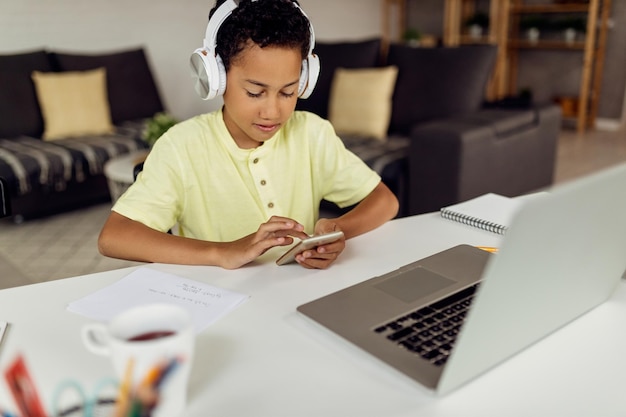 Little black boy using smart phone while learning at home