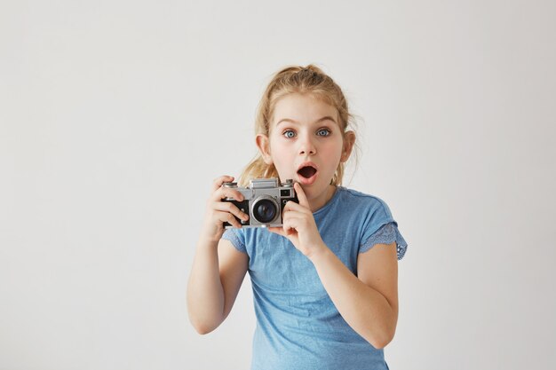 Little blond miss with blue eyes was taking family photo of parents with film camera when dad slipped and fell down. Child looking frightened that parent get hurt.