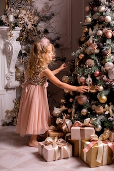 금발 소녀는 아름다운 인테리어에 크리스마스 트리를 장식