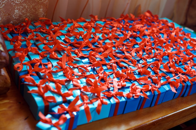 Free photo little blue gift boxes with red ribbons lie on a table