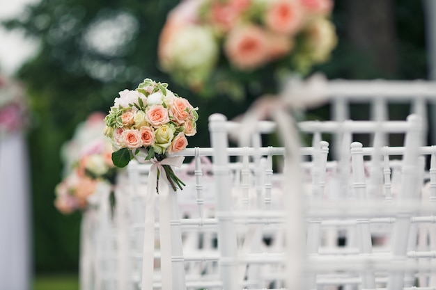 Free photo little bouquets twined to the backs of white chairs