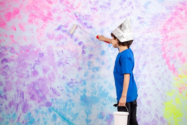 little boy in blue t-shrit painting walls