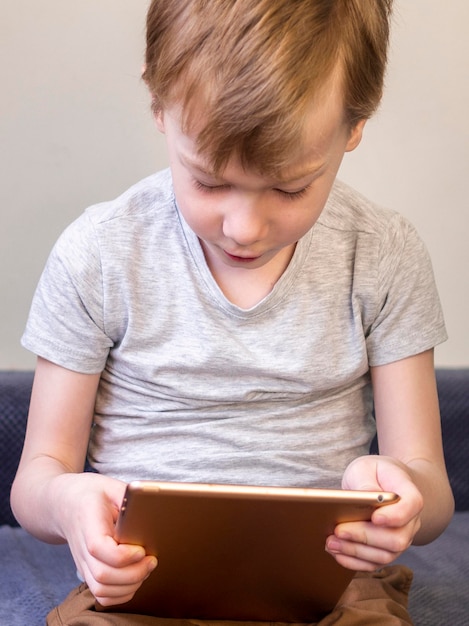 Free photo little boy checking a tablet