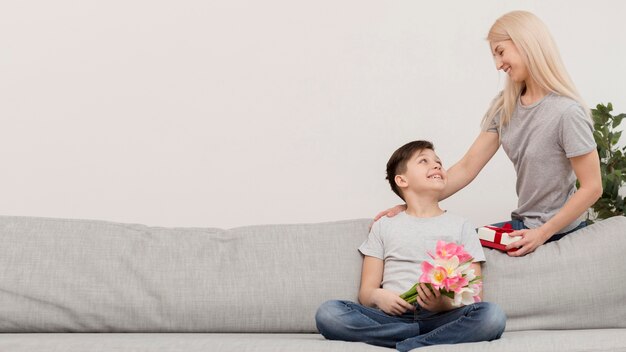 Little boy on couch with gifts for mom