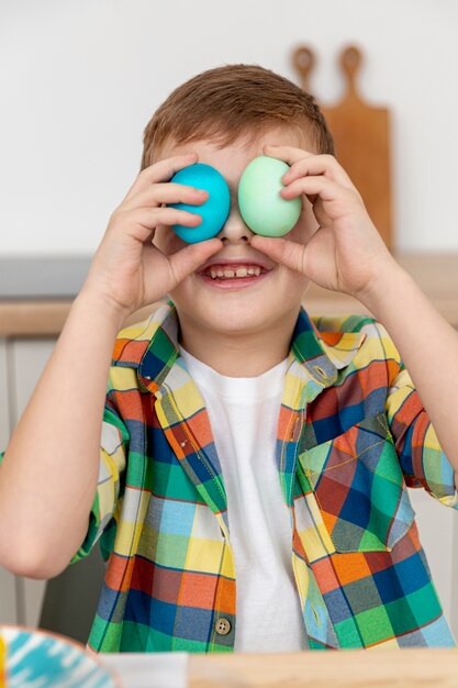 Little boy covering eyes with painted eggs