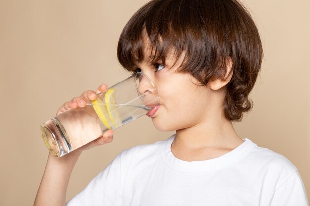 小さな男の子かわいいピンクのレモンジュースを飲む